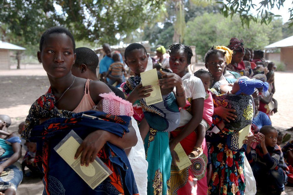 Women carrying children queue at an MSF mobile clinic in the village of Nanili. (December, 2021).