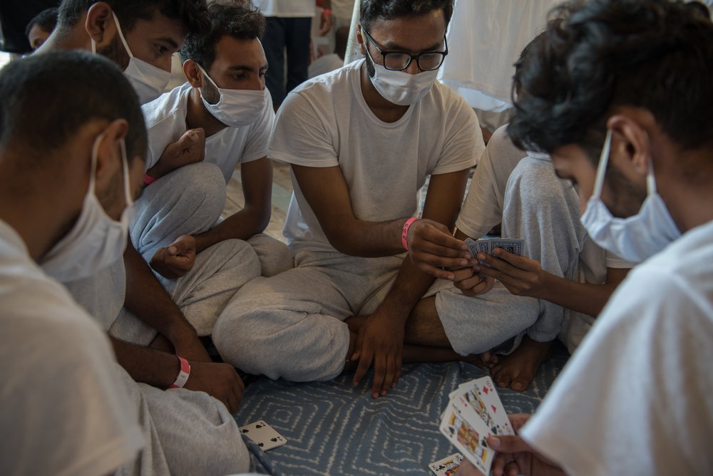 A group of rescued people play cards in the afternoon. They are part of the 22 persons from Pakistan on board the Geo Barents. Geo Barents, 19.08.21.