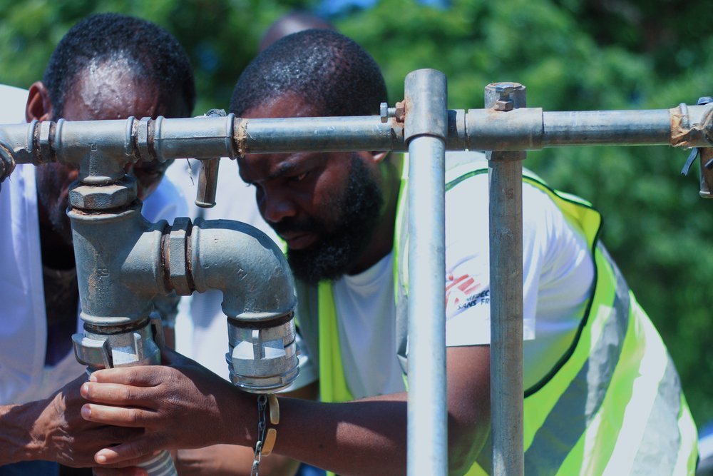 A fieldworker is seen connecting a water pipe to a pumping station at Bangula camp where MSF is providing WASH facilities for people diplaced by Tropical Cyclone Ana. (February, 2022).