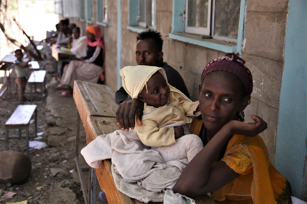 Newly displaced people sit at wooden benches at Kundeya school in the city of Axum, central Tigray.