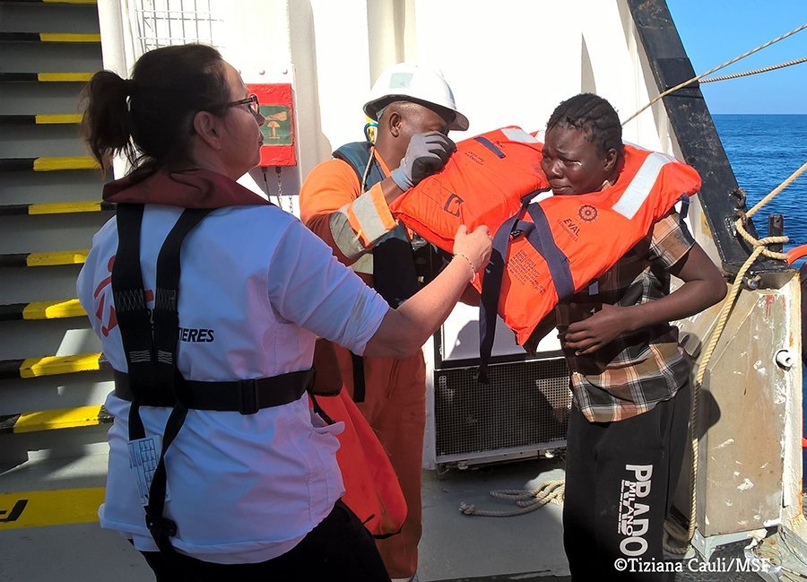 A woman is brought on board the Aquarius with the help of MSF staff.