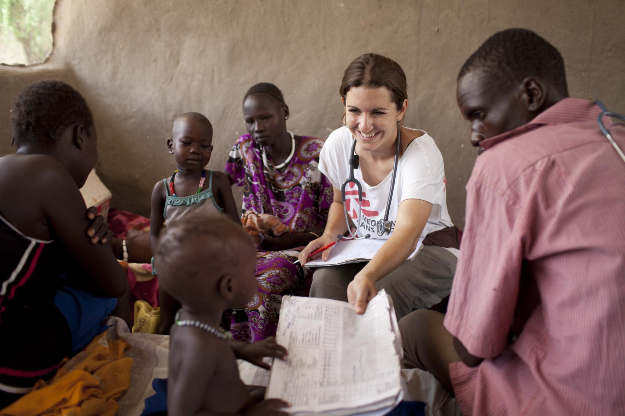 MSF health workers sitting with locals and children