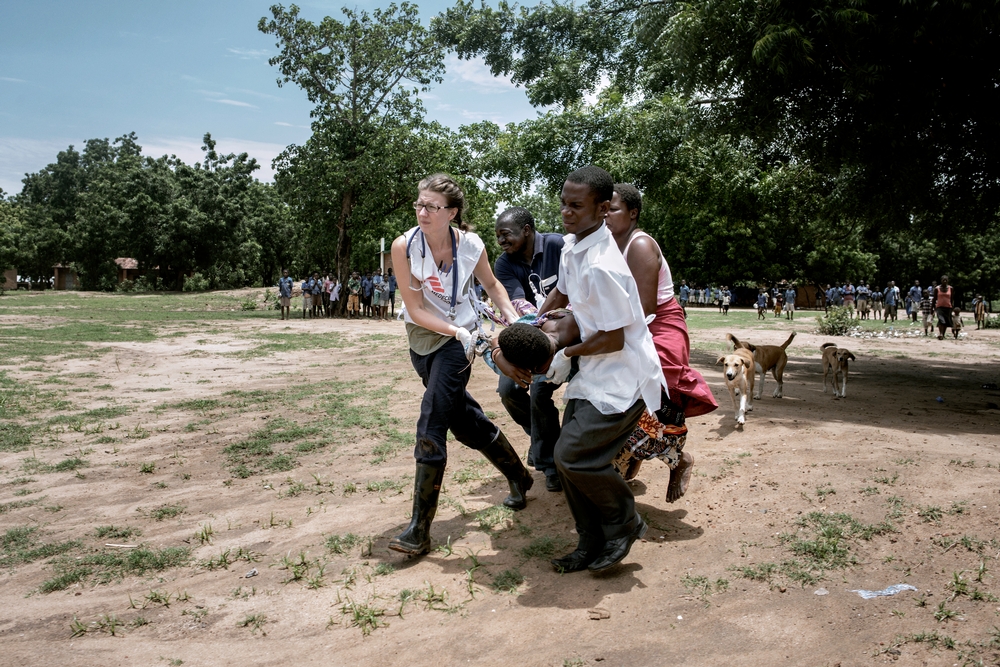 A group of people, lead by an MSF health worker, carrying a patient