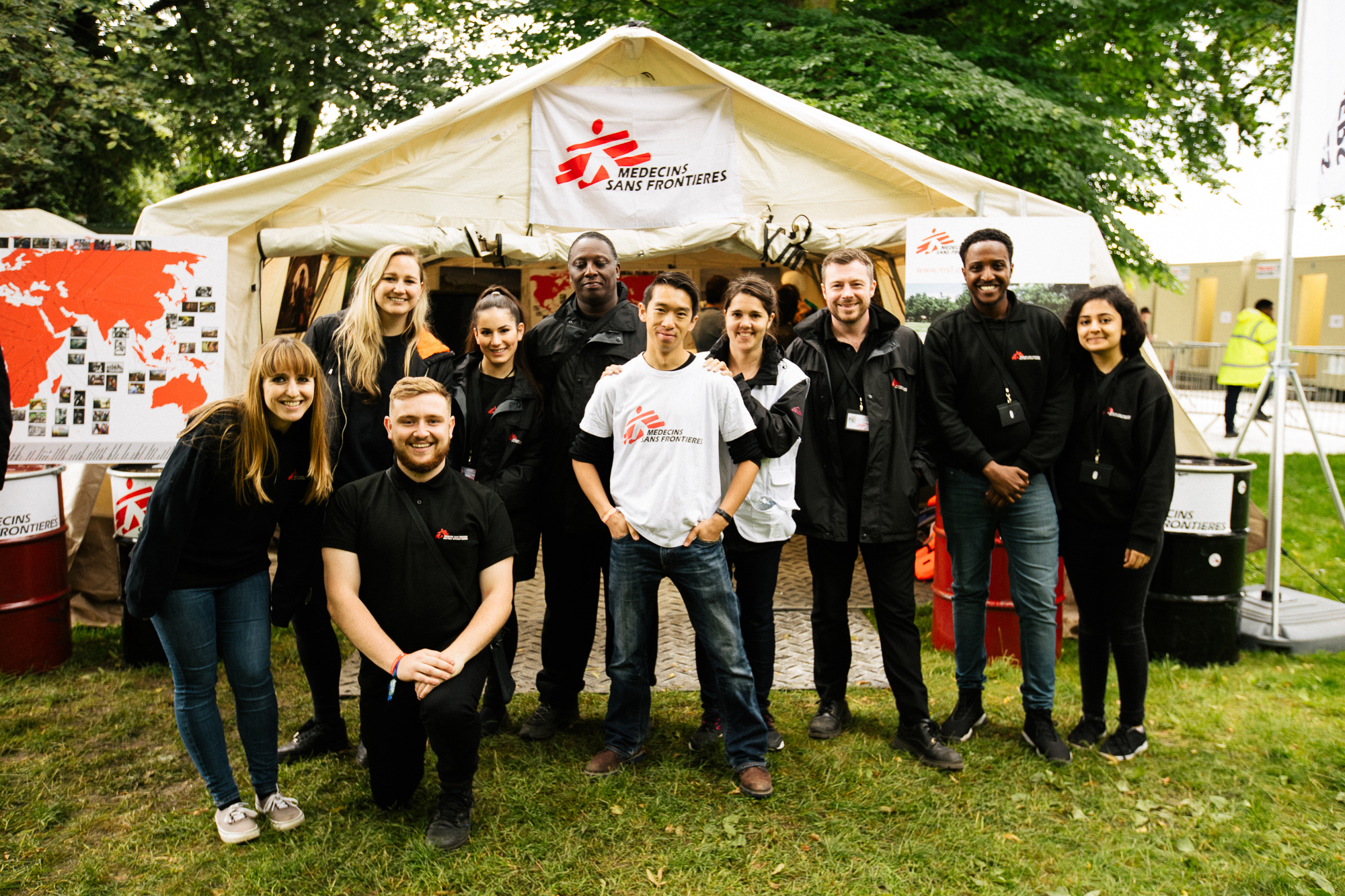A group of fundraisers wearing MSF clothing pose for a photo outside a large MSF tent